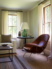 a brown leather egg-shaped chair with a pillow is a cool and chic idea for a modern space, it welcomes to sit in