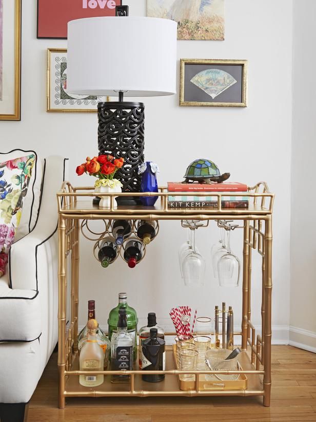 a chic gold bar cart with bottle and glass holders, with a gold tray and gold edge glasses