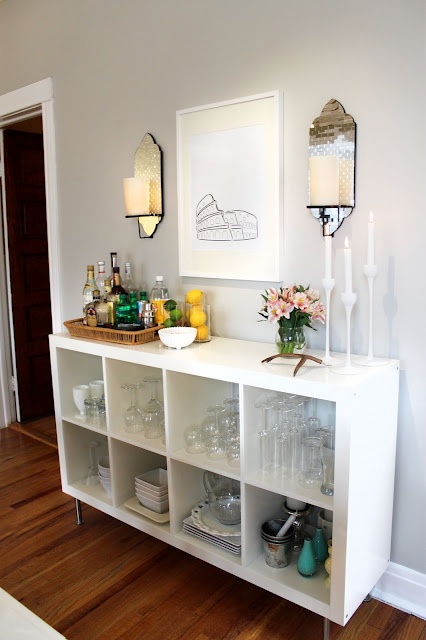 an IKEA unit hacked into a stylish modern home bar, with candles, glasses and everything necessary including citrus
