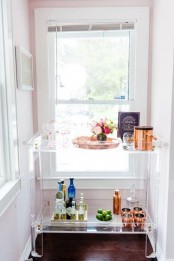 a modern home bar of clear acryl, with bright blooms and copper barware plus pink glasses for a chic and fresh look
