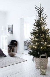 a modern Christmas tree with lights and in a woven basket is a stylish idea for a modern or Scandinavian space
