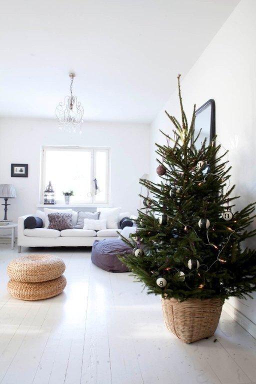 a modern Christmas tree in a basket, with lights, black, white and copper ornaments is a simple and cool idea for a modern space