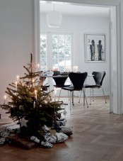 a modern Christmas tree decorated with only white ornaments and candles plus gifts wrapped in black and white paper is a wow idea