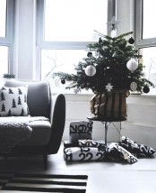 a modern Christmas tree decorated with only red and white ornaments of various looks and shapes, packed gifts and a black and white printed pillow for a modern or Scandi space