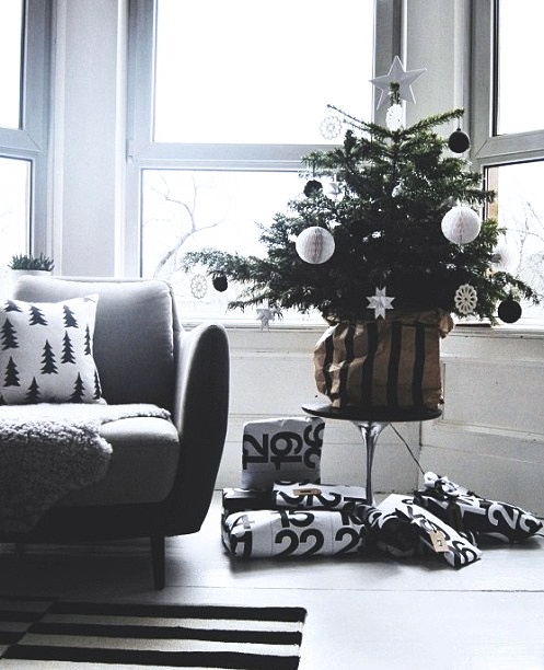 a modern Christmas tree decorated with only red and white ornaments of various looks and shapes, packed gifts and a black and white printed pillow for a modern or Scandi space