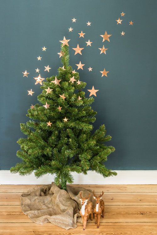 a Christmas tree with no decor except for a bit of gold stars going up to the wall and continuing there is a gorgeous idea for a modern or minimalist space