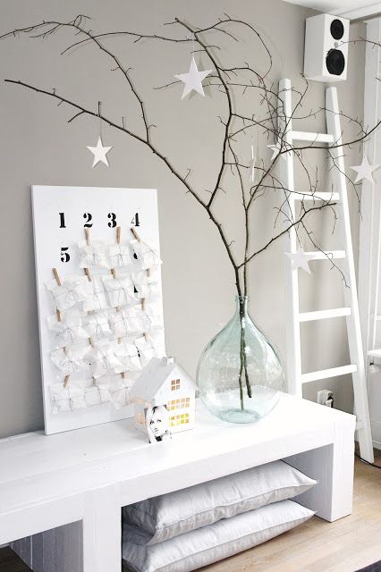 simple branches with white paper stars placed into a large bottle as an alternative minimalist Christmas tree