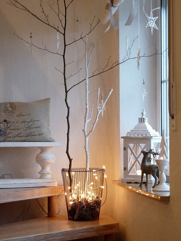 black and white branches, lights and pinecones in a wire basket and paper ornaments on all the branches