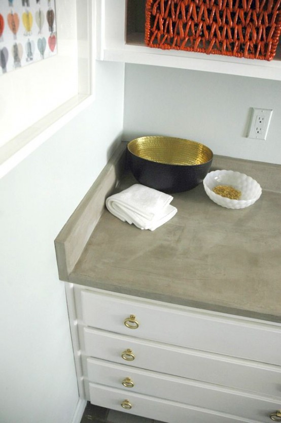 a modern white kitchen with gold handles and a concrete countertop is chic and stylish