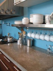 a blue kitchen with chocolate brown cabinets and a polished concrete countertop looks bold and catchy