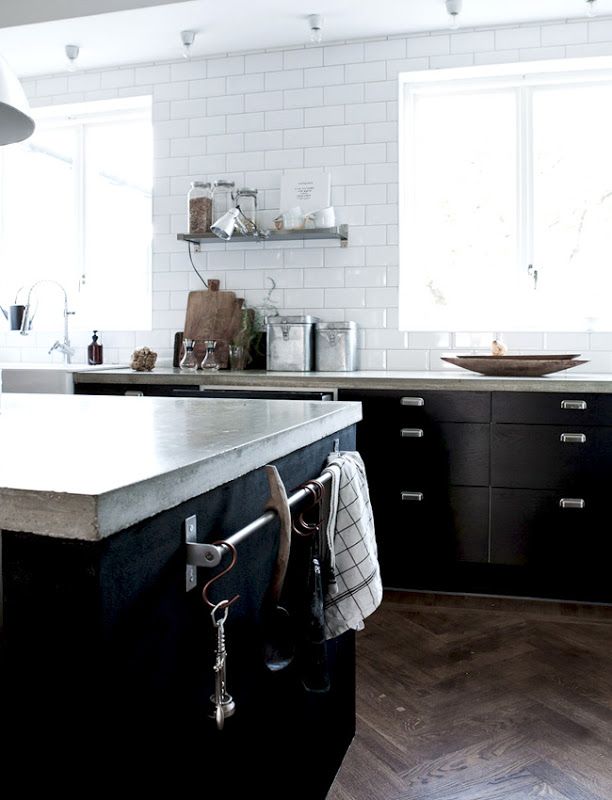 a Scandinavian kitchen with black cabinets, a white tile backsplash and concrete countertops looks ultra modern and very fresh