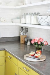 a bright yellow kitchen with a white tile backsplash and a polished concrete countertop that makes the space look more industrial