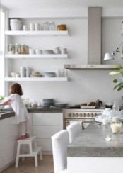 a white minimalist kitchen with concrete countertops and stainless steel appliances looks ultra-modern and very laconic