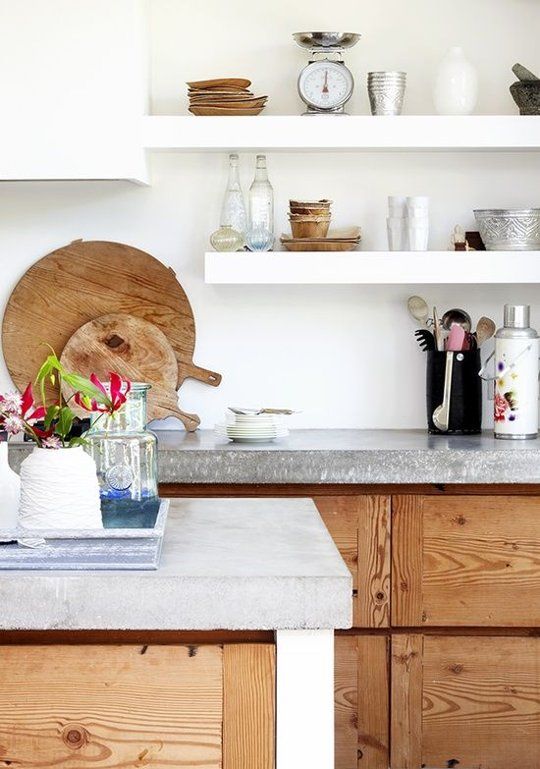 a modern kitchen with wooden cabinets, white walls and shelves and concrete countertops for an edgy touch