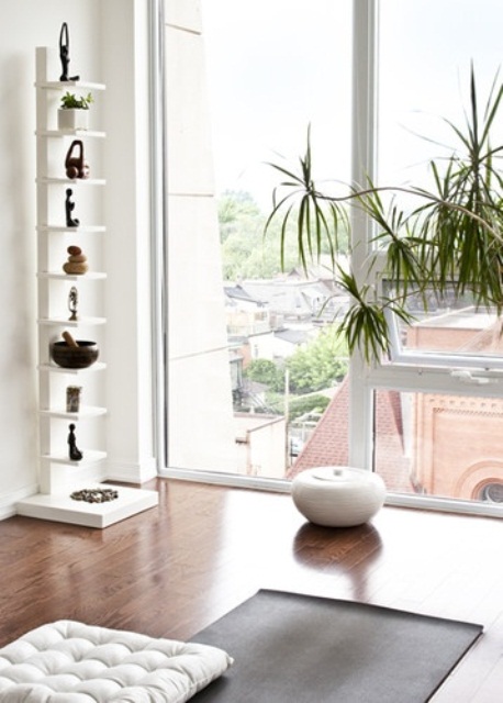 a minimalist white meditation space with potted greenery and layered rugs