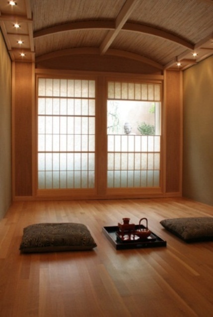 a clean Asian-inspired meditation room with rugs and pillows and much light