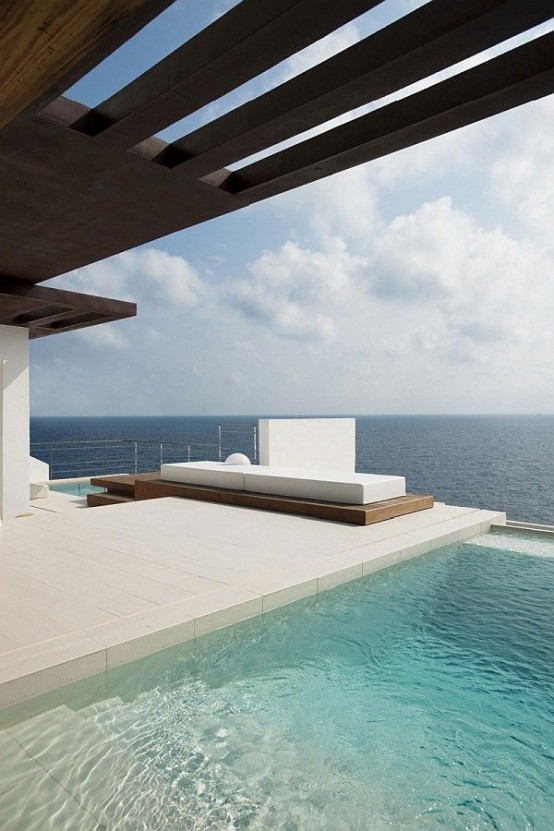 a minimalist terrace with a white deck, a wooden platform and a bed, with two pools and a gorgeous sea view is ultimate