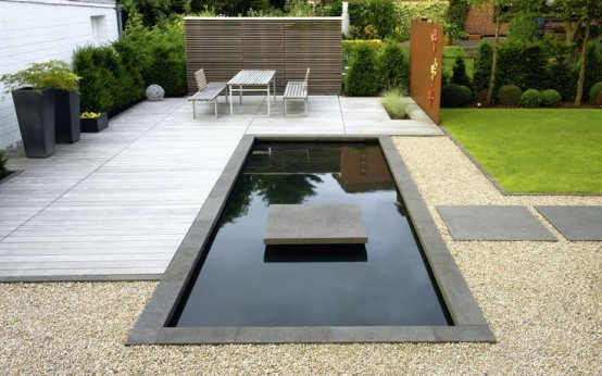 a minimalist space with a wooden deck, garden furniture, a pool with concrete stone tiles and tall modern planters with lots of greenery