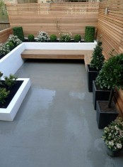 a minimalist patop with a tile floor, potted plants and blooms and a built-in wooden bench plus wooden plank screens