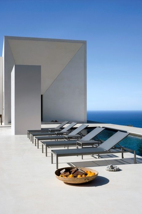 a minimalist terrace with a sea view, with metal loungers and a basket with fruits is a gorgeous space with plenty of style