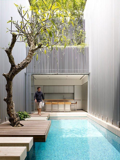 an inner courtyard with a pool and a wooden deck of several steps plus a tree growing here is a gorgeous space