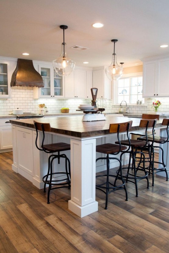 a white farmhouse kitchen with shaker style cabinets, butcherblock countertops, a large kitchen island with a seating space and vintage tall stools