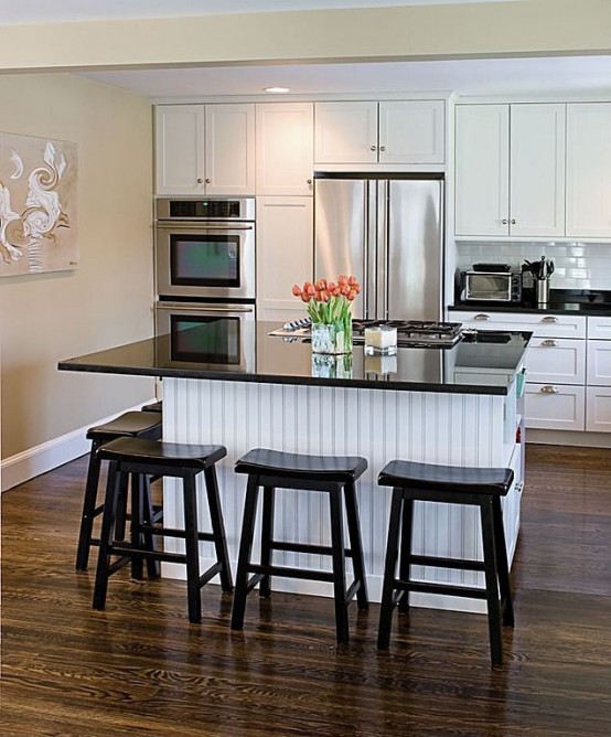 a modern black and white farmhouse kitchen with shaker style cabinets and a small planked kitchen island and tall black stools