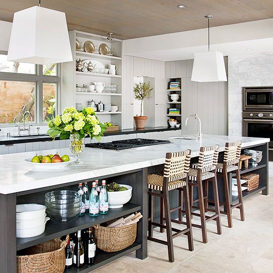 a welcoming farmhouse kitchen with an oversized kitchen island in graphite grey and white, with open storage shelves and tall stools for eating here