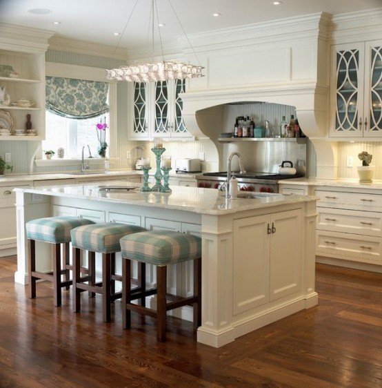 a white farmhouse kitchen with shaker style cabinets, white stone countertops, a large kitchen island with a seating space and striped stools