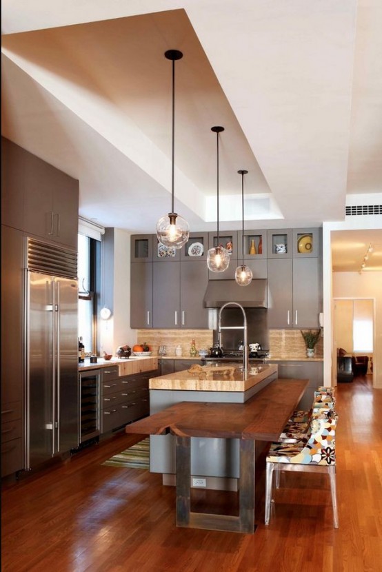 a modern grey kitchen with a wooden backsplash and white stone countertops, a grey kitchen island with an integrated wooden dining table for eating here