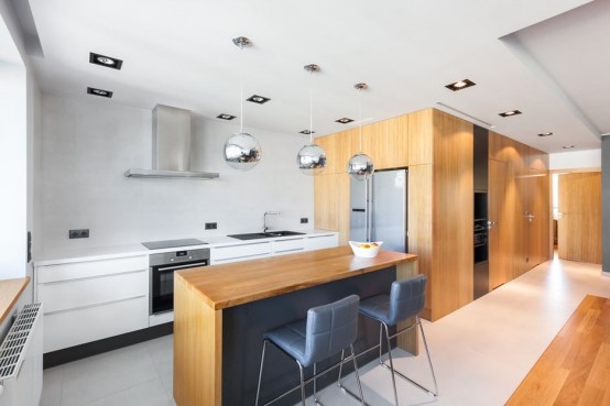 a minimalist white kitchen with sleek cabinets, a stained and black kitchen island and grey stools for having meals and drinks here