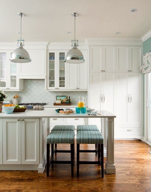 a white farmhouse kitchen with a large kitchen island with a seating space, metal pendant lamps, a white arabesque tile backsplash