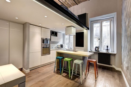 a small modern kitchen in neutrals, with sleek cabinets and a small kitchen island that doubles as a dining table