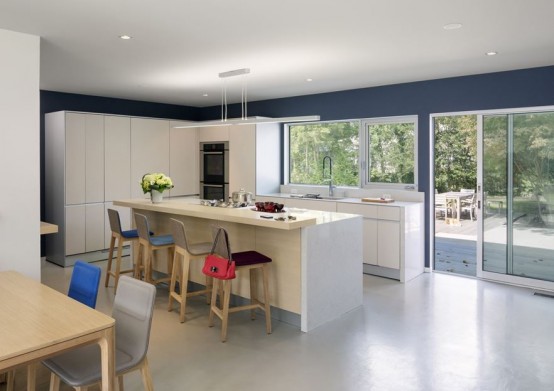 a modern white kitchen with sleek cabinets, a large kitchen island with a raised countertop for eating and having drinks here