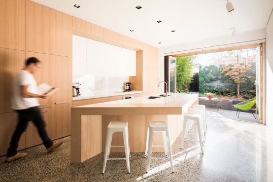 a sleek minimalist light-stained kitchen with white countertops and a backsplash, a large geometric stained kitchen island and white stools