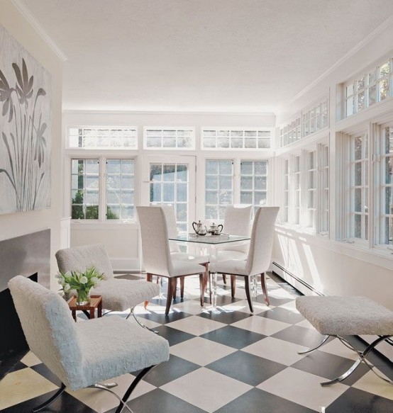 a modern neutral sunroom with a series of windows, a fireplace, a white dining space and white chairs is a lovely space to be in
