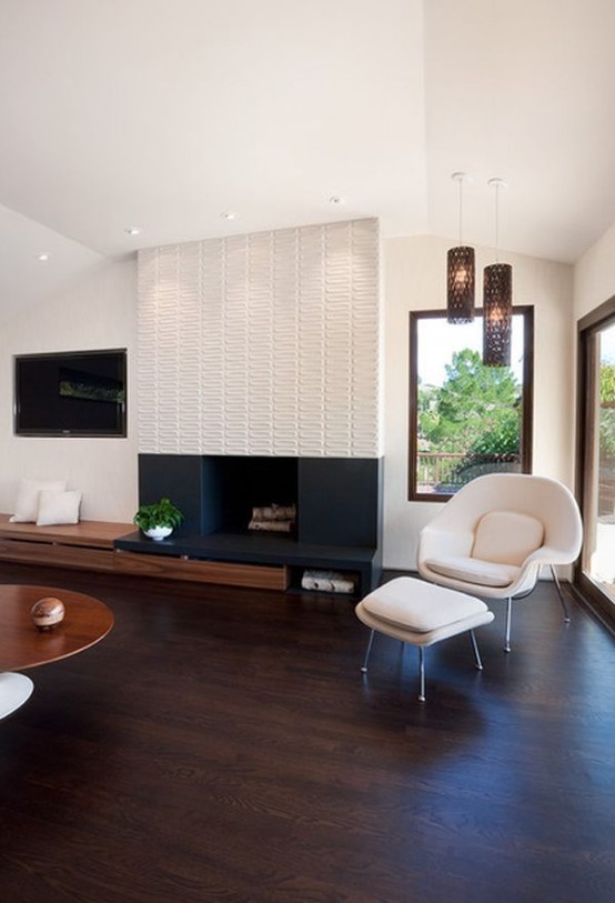 a modern living room with contrasting decor, a built-in fireplace with a patterned surround, a built-in bench, a creamy chair and a footrest, pendant lamps and a low coffee table and built-in lights