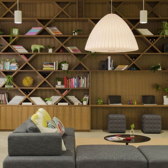 a modern home library with a shelving unit that takes the whole wall and some comfy sitting furniture