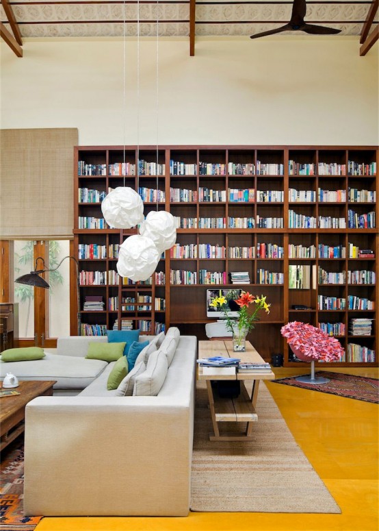 a large home library with an oversized bookshelf unit, modern furniture and shades on the windows