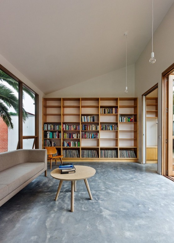 a modern home library with a large shelving unit, comfy contemporary furniture and a glazed wall