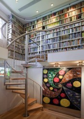 a modern library with bookshelves built-in on the second floor, a bold abstract painting – just add a chair and voila