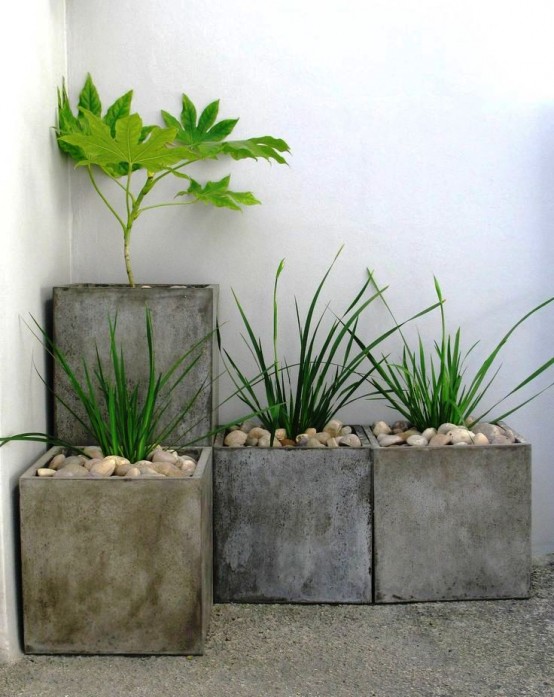 a concrete square planter arrangement with greenery and pebbles is a cool minimalist decoration for a backyard