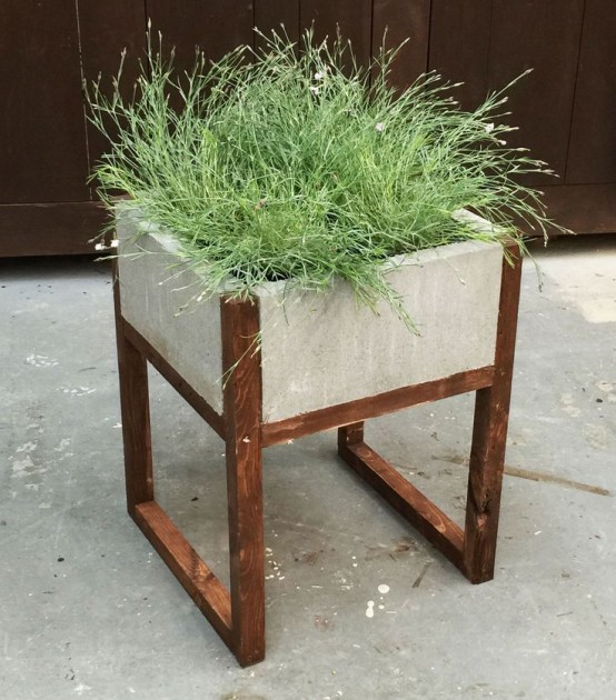 a concrete planter on wooden legs with grasses is a stylish modern piece for a modern outdoor space