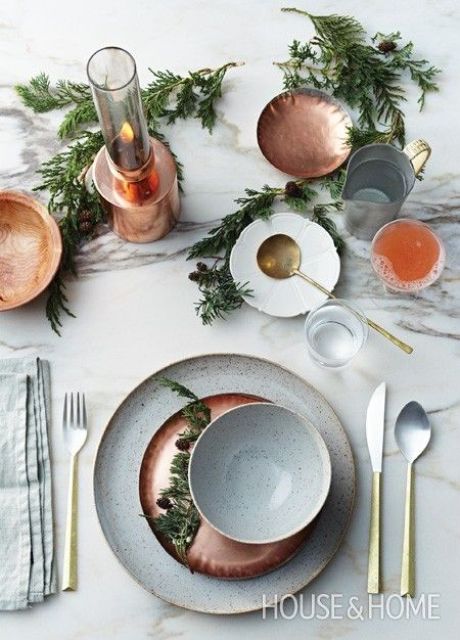 a modern Thanksgiving tablescape with speckled porcelain, greenery, candles and cutlery is a chic idea