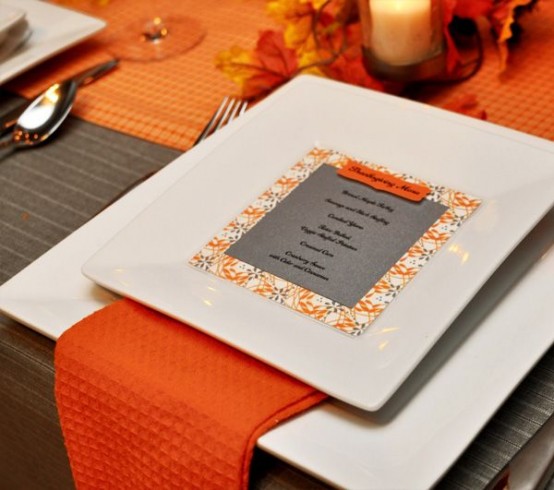 a modern colorful Thanksgiving tablescape in grey and orange, with square plates, a grey card and a bright orange runner and napkins