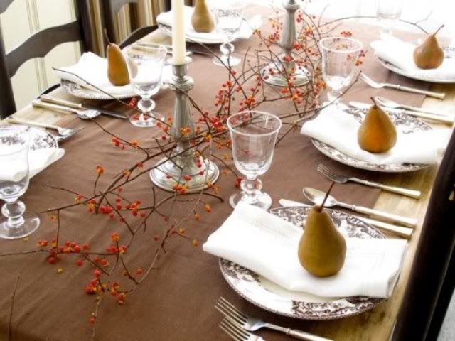 a simple and modern Thanksgiving tablescape with a brown table runner, berries on branches, pears and candles plus patterned porcelain