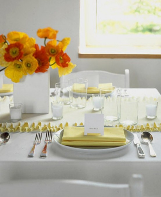 a bright Mother's Day tablescape with a yellow runner, napkin and bold yellow and orange blooms and everything else styled in white