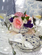 elegant vintage-inspired wedding tablescape with a lace tablecloth. bright blooms, blue printed porcelain and gold-rimmed glasses