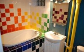 a white bathroom with a navy accent wall and with super bright tiles for an accent is a creative idea for a kid’s space