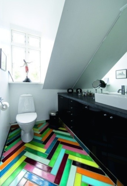 an attic bathroom in white, with a large black vanity for storage and a colorful herringbone tile floor is a fun and cool space to be